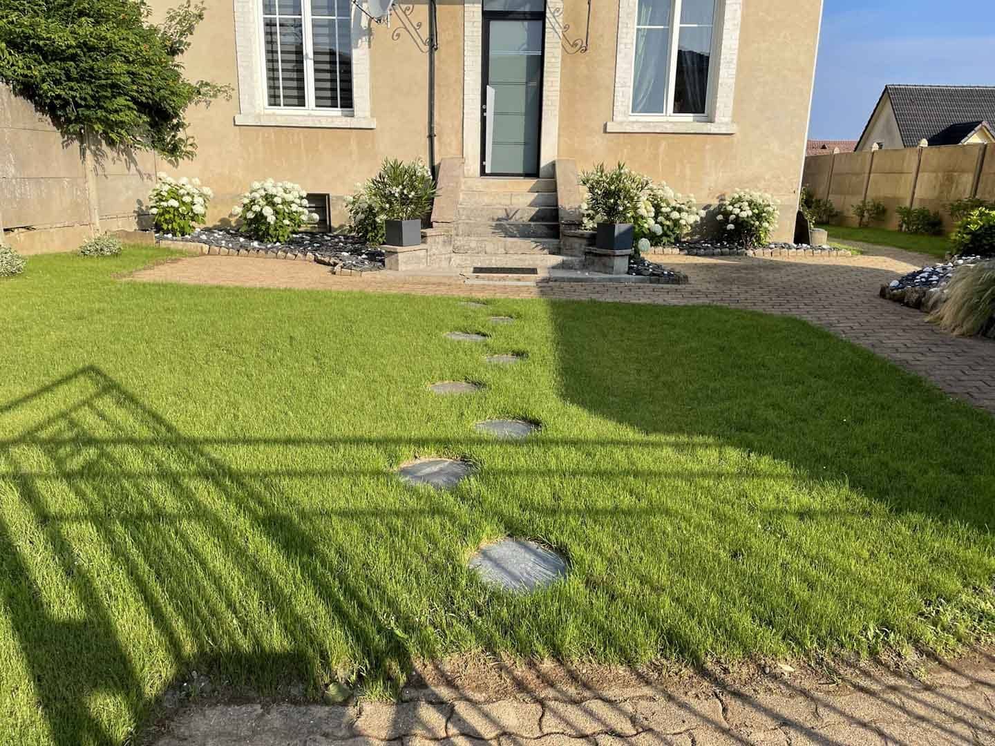 Pelouse avec pas japonais et massifs d'hortensias devant une maison
