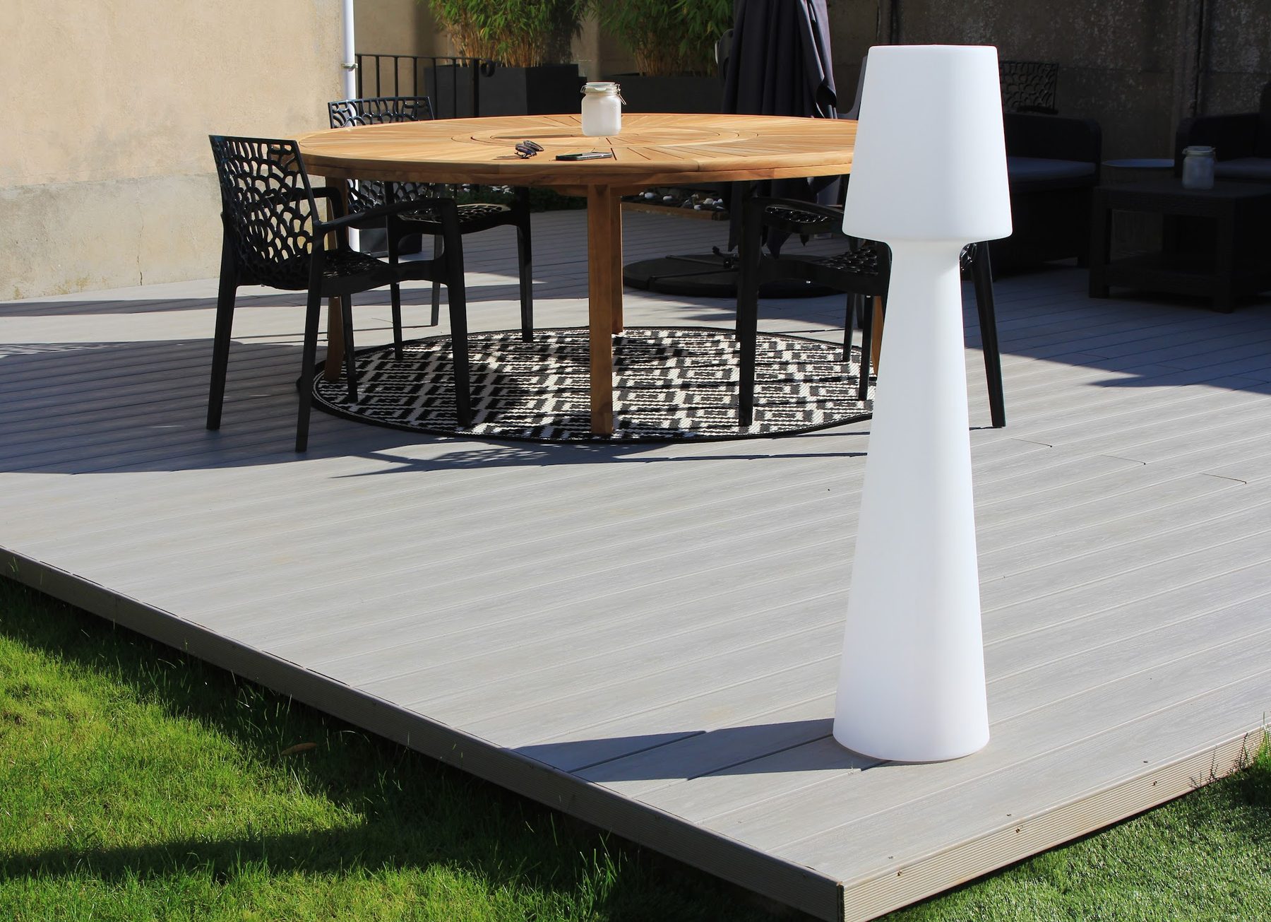 Terrasse en lames grises avec table ronde en teck